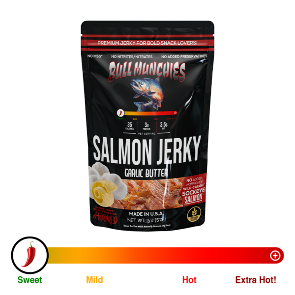 Packaging of Bull Munchies Wild-Caught Salmon Jerky in Garlic Butter flavor. The design features a detailed illustration of a large salmon in mid-leap against a red background. Text on the packaging highlights ‘No Added Hormones’ and the weight of the package as 2.0 oz (74g).